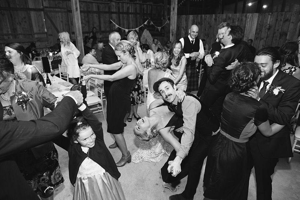 Wedding guests dancing and celebrating on a dimly lit dance floor.