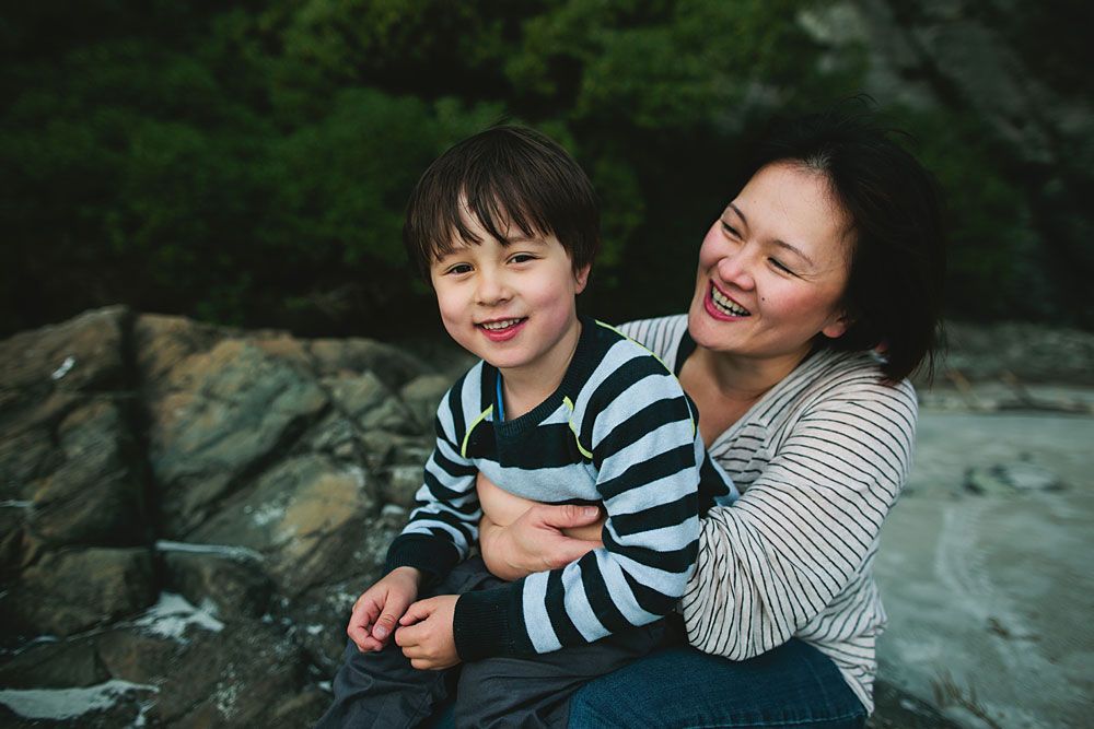 Intimate family moments captured in a natural outdoor setting with rocks and greenery.