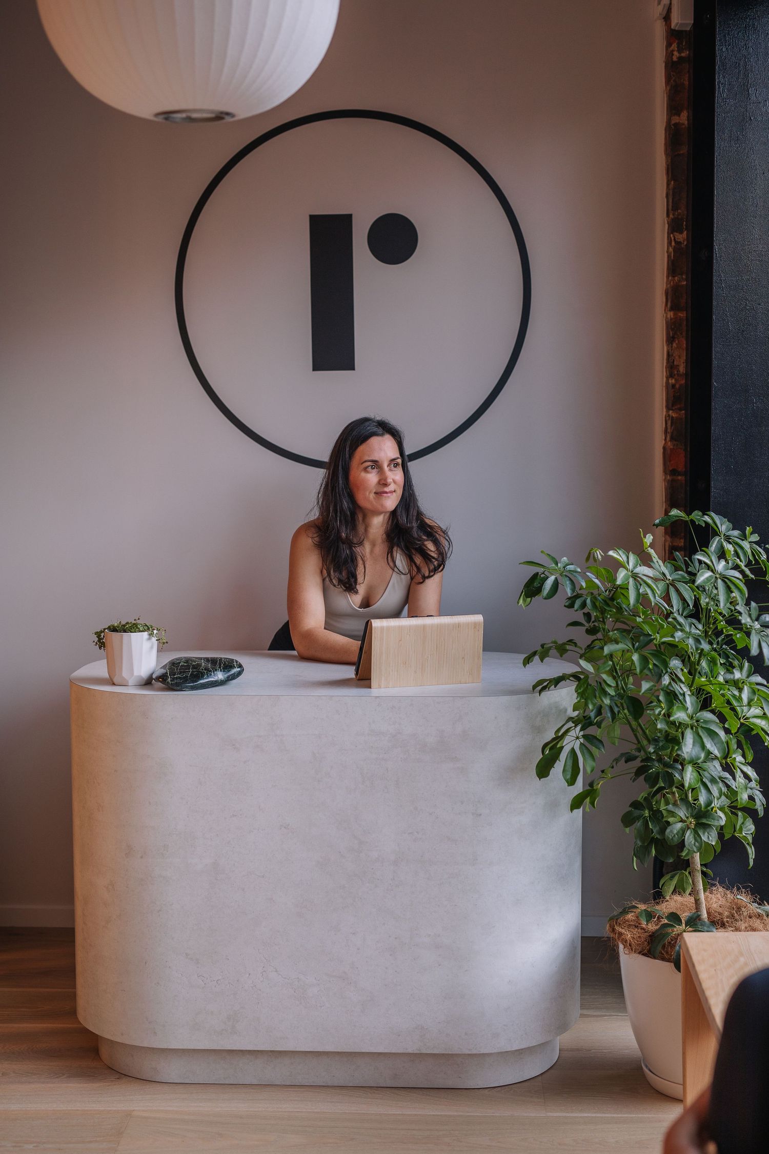Modern concrete reception desk with minimalist design and indoor plants in an office setting.