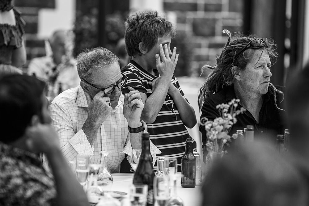 Wedding reception guests react emotionally during speeches in black and white photography.
