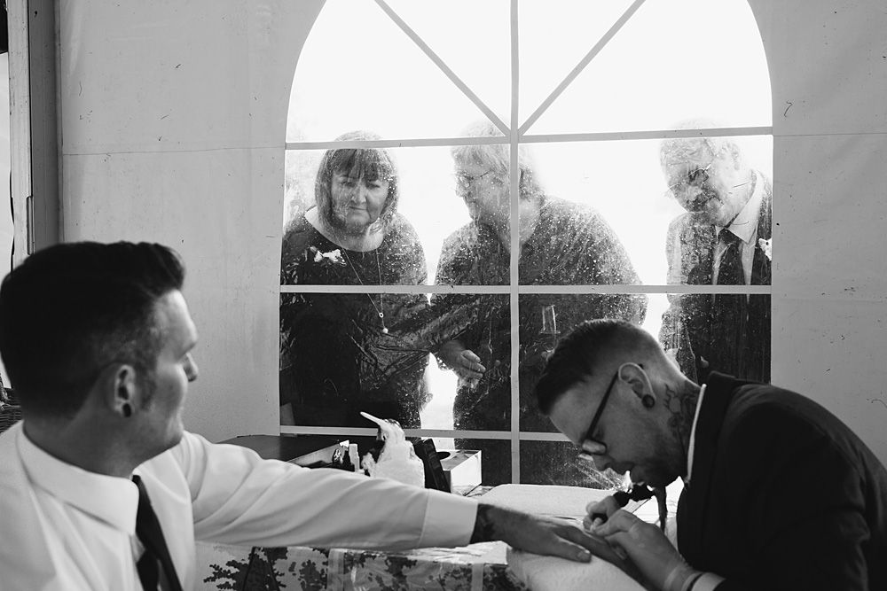 Black and white photo of children peeking through a tent window at a wedding reception.