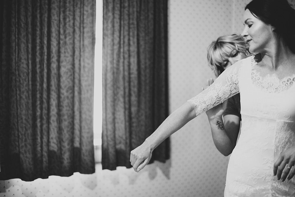 Black and white photo of a bride getting ready in an elegant room.