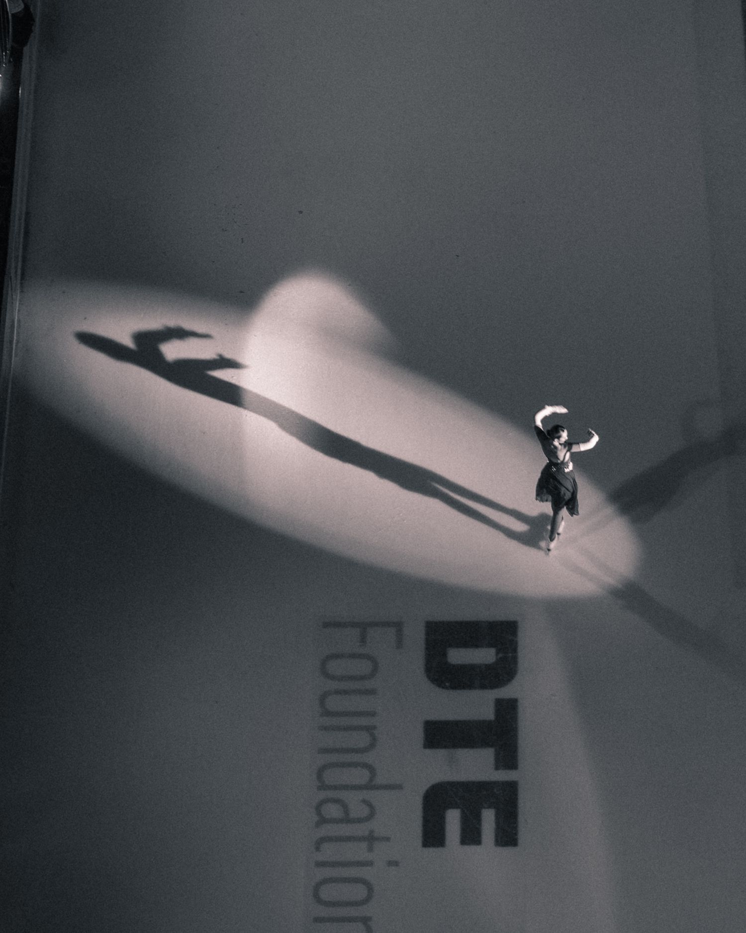 Artistic black and white photo of small figure casting large shadow against DTE Foundation text.