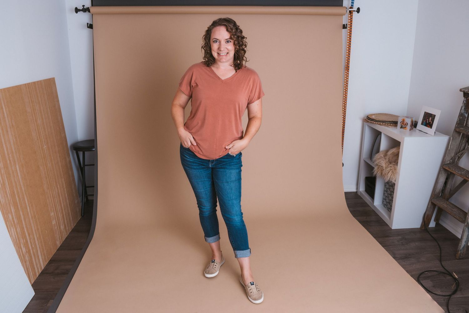 Professional and inviting full-body portrait of photographer in her Macomb, Michigan home studio, reflecting warmth and creativity.