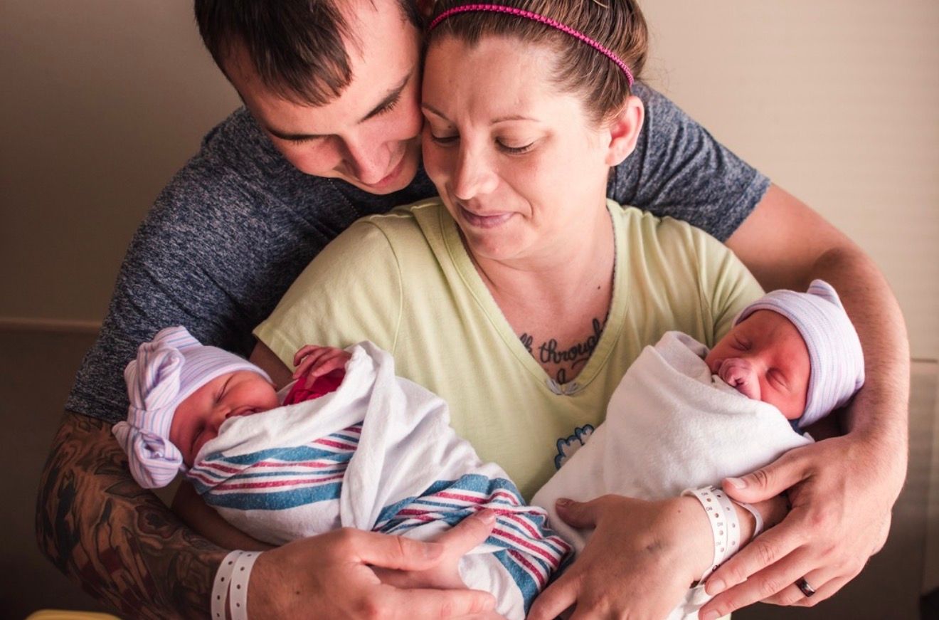 Parents look lovingly at their new babies for their fresh 48 session in Royal Oak MI