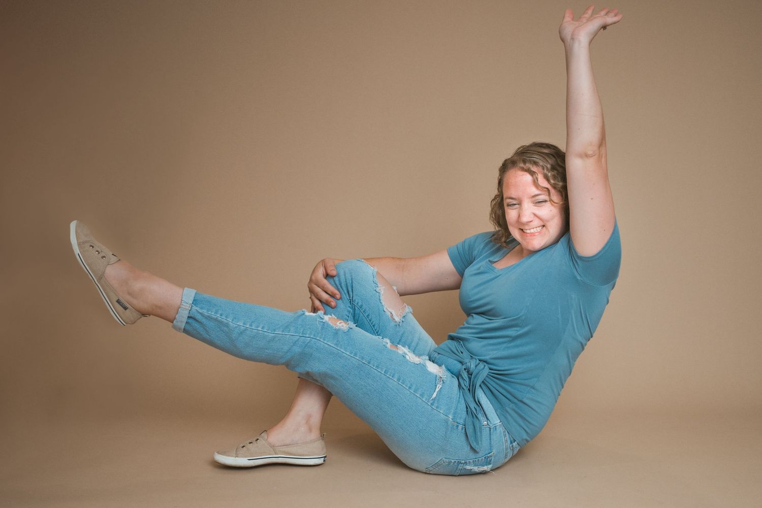 Playful and inviting full-body portrait of photographer in her Macomb, Michigan home studio, capturing her fun and approachable spirit.