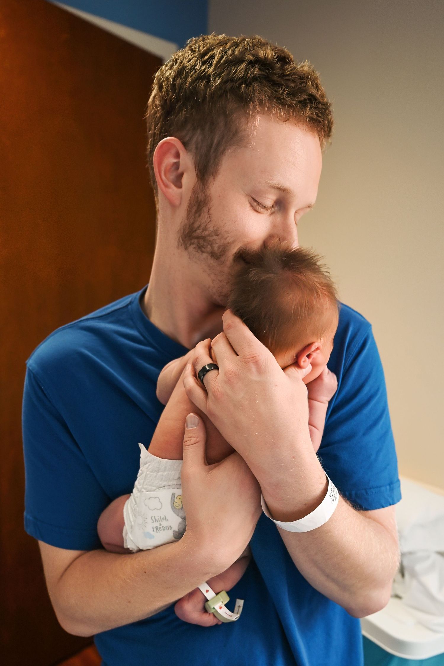 Dad holds his newborn during his fresh 48 photography session at a hospital in Troy Michigan. Dad holds the baby so his face is not in view
