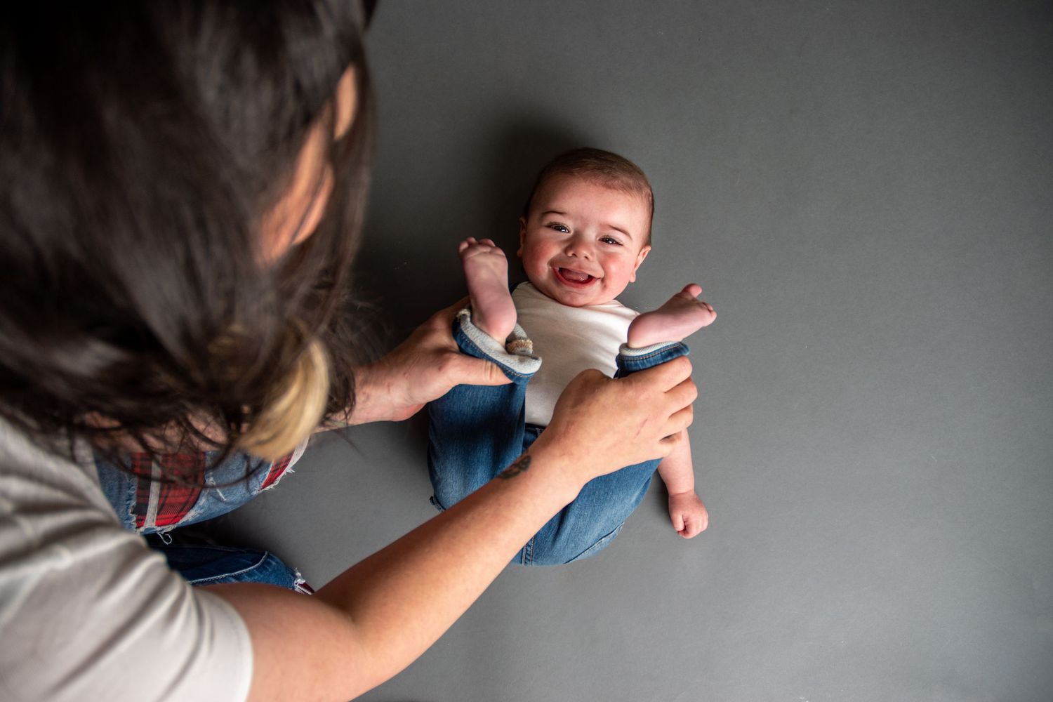 A mother holding her laughing baby up in the air during a professional studio photo session.