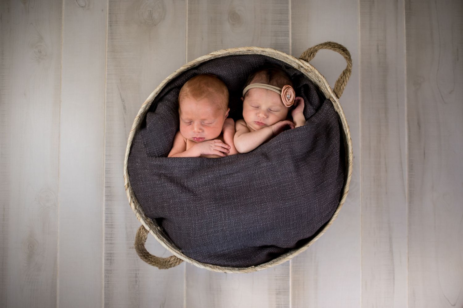Twins laying in a basket sleeping at their in home newborn session in Saint Clair Shores Michigan