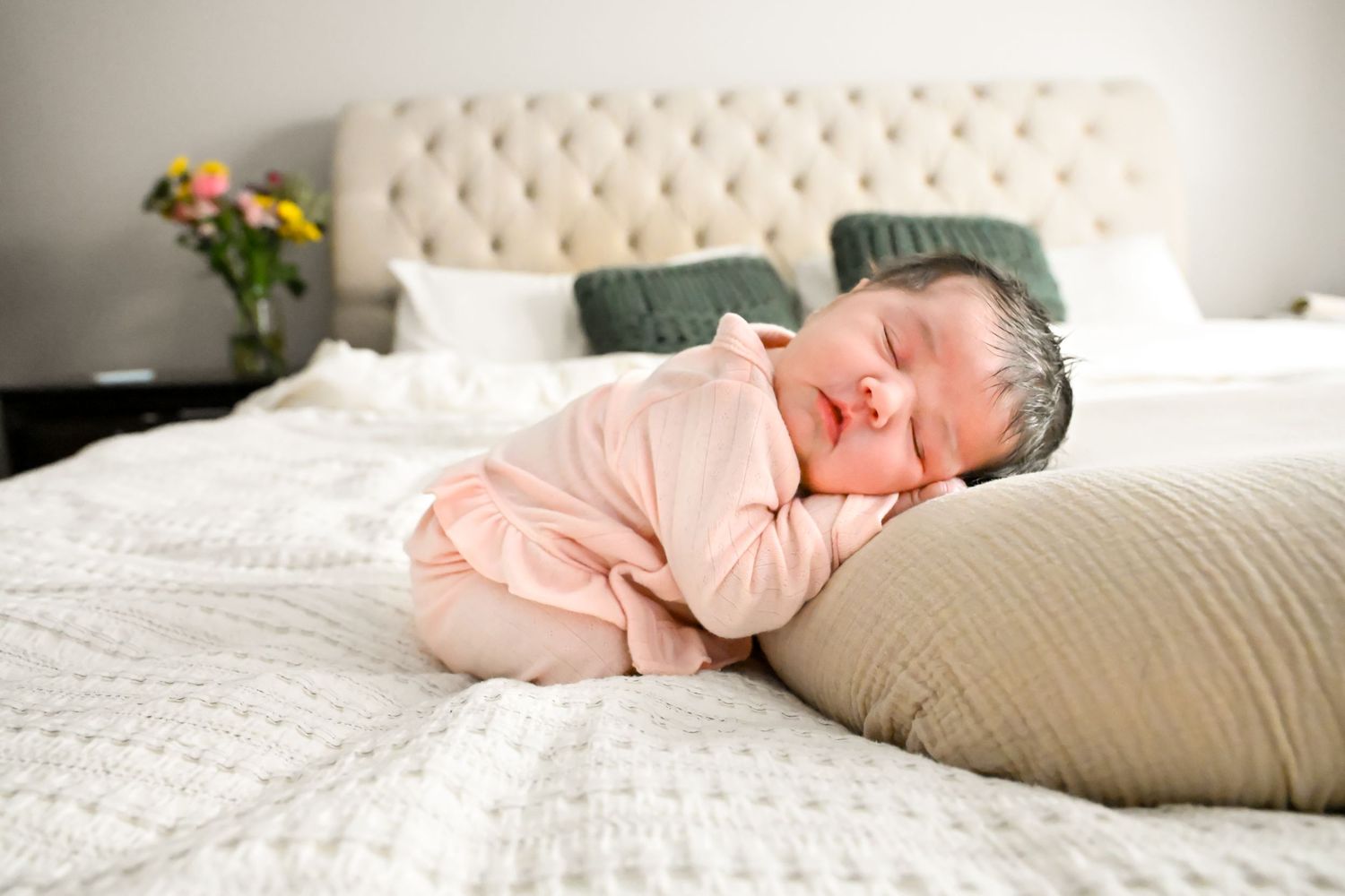Newborn baby posed on her parents bed for her in home newborn session. She is sleeping peacefully