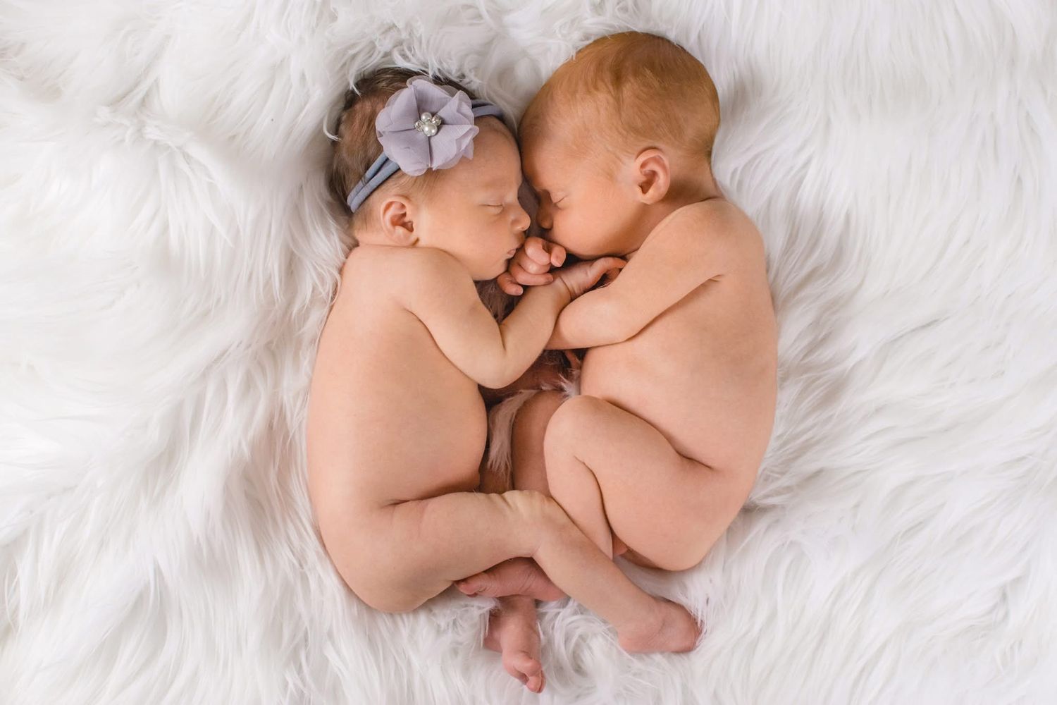 Twins snuggled on a furry blanket at their newborn session taken at home in Saint Clair Shores Michigan.
