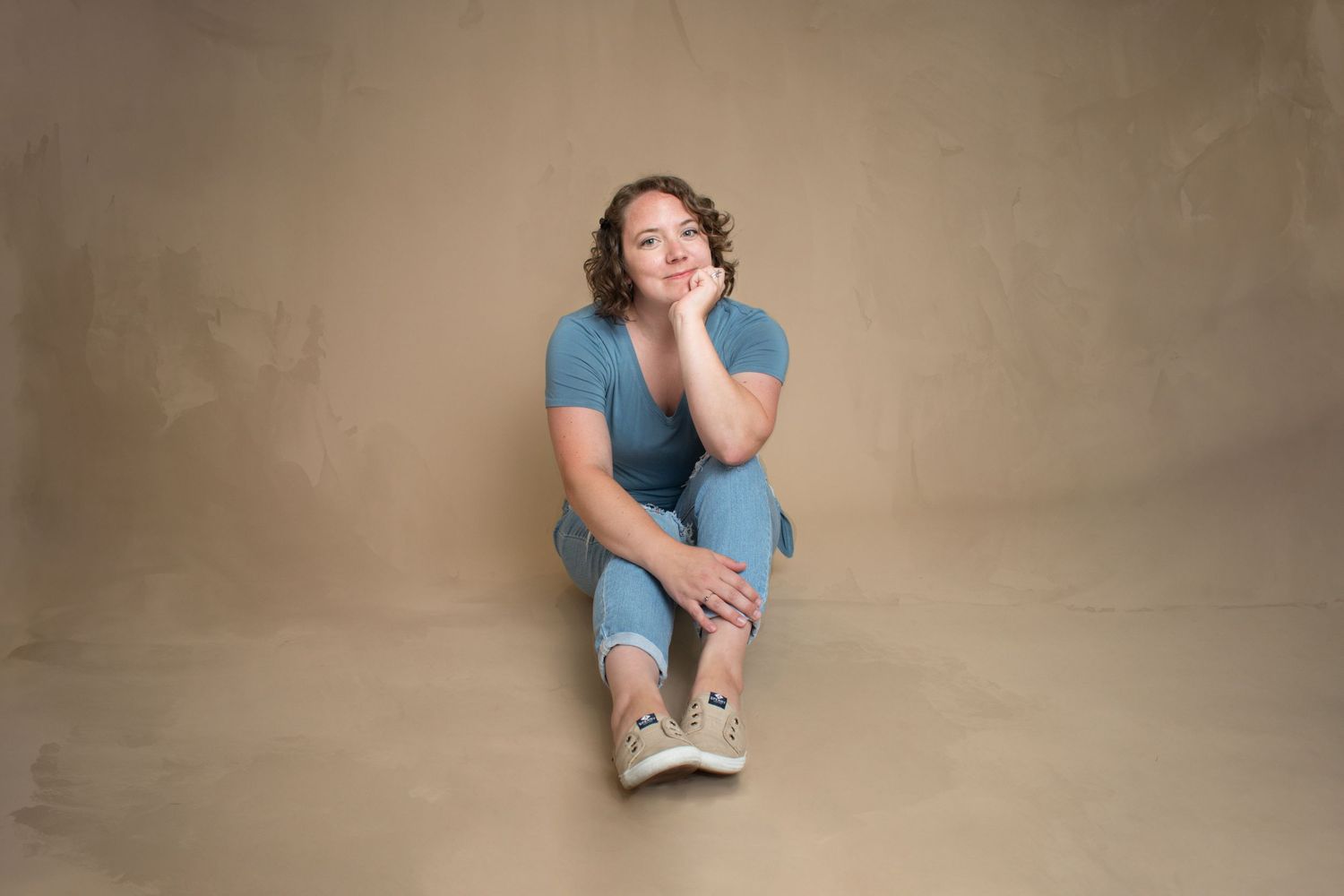 Full-body headshot of photographer in her Macomb, Michigan home studio, showcasing a warm and approachable creative professional
