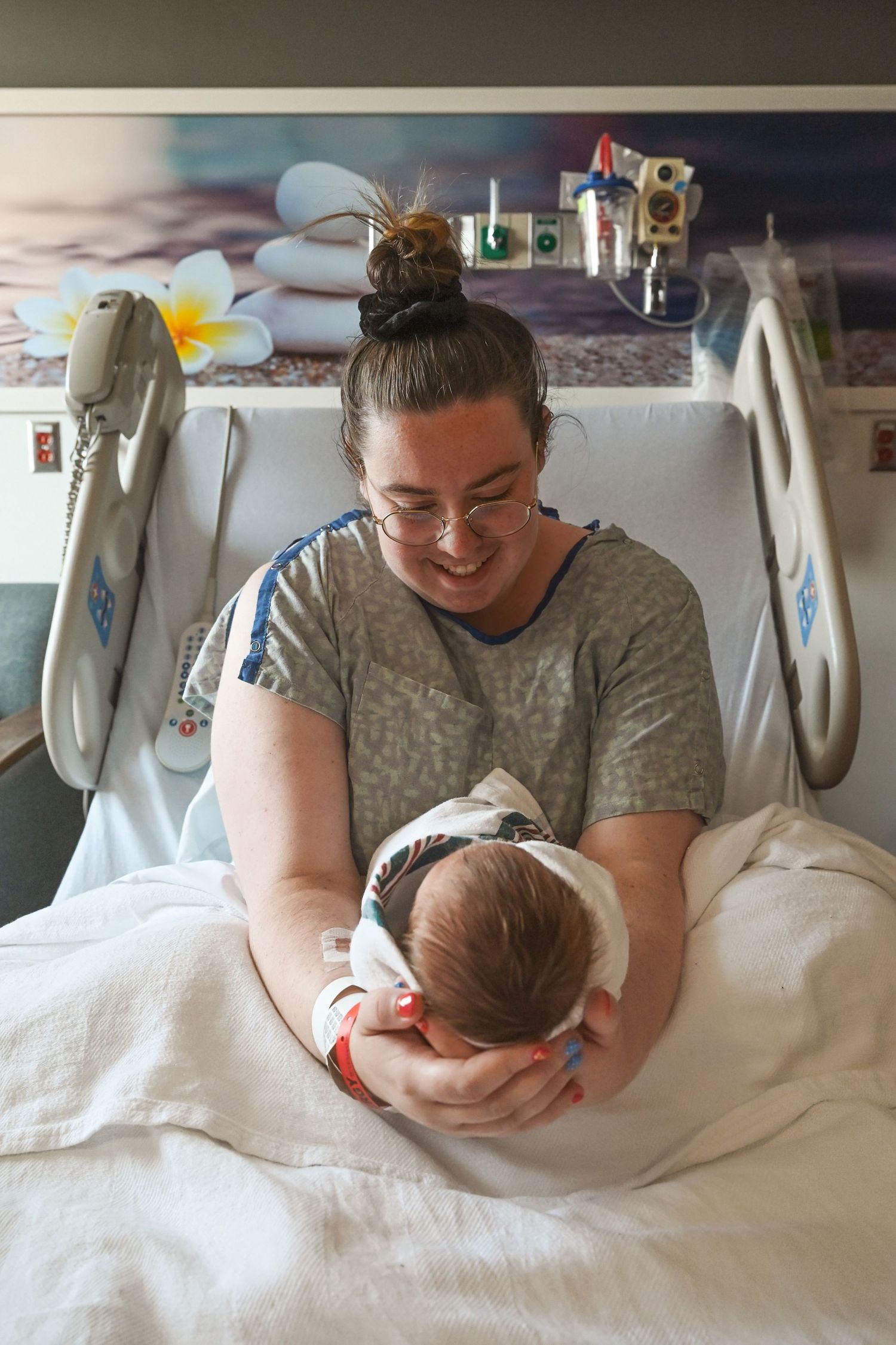 Mother at a troy Michigan hospital fresh 48 session holds her newborn son from her recovery bed She positions him so his face is not visible