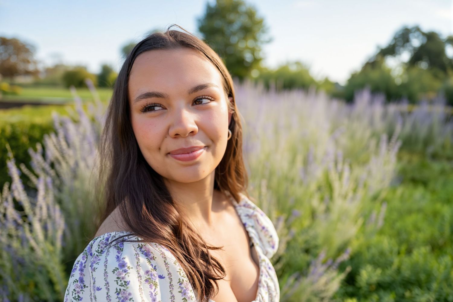 Young woman with brown hair gazes upward near a purple lavender field on a sunny day.