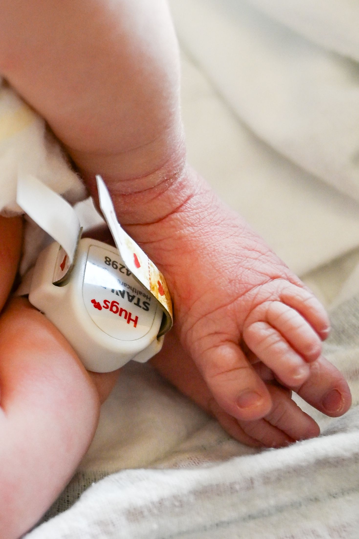 Close-up of a newborn baby foot wearing a hospital Hugs security tag on an ankle band.