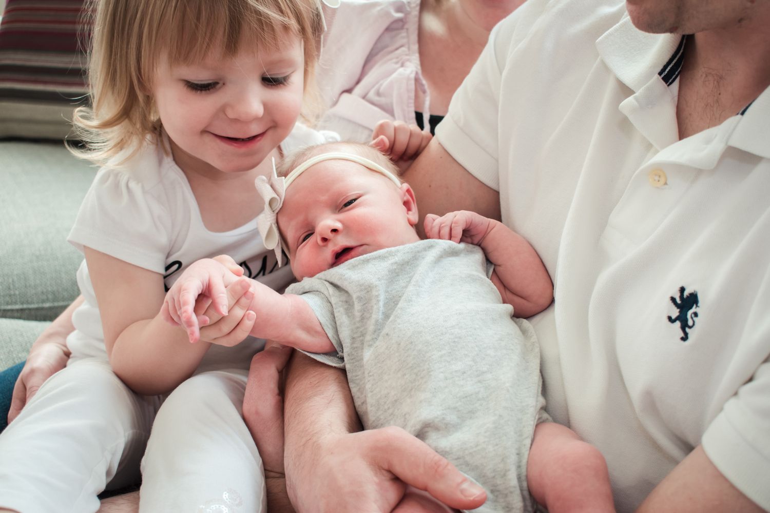Cozy family snuggle on a couch during a combined Welcome Baby, Newborn, and Family session in Rochester, Michigan capturing connection