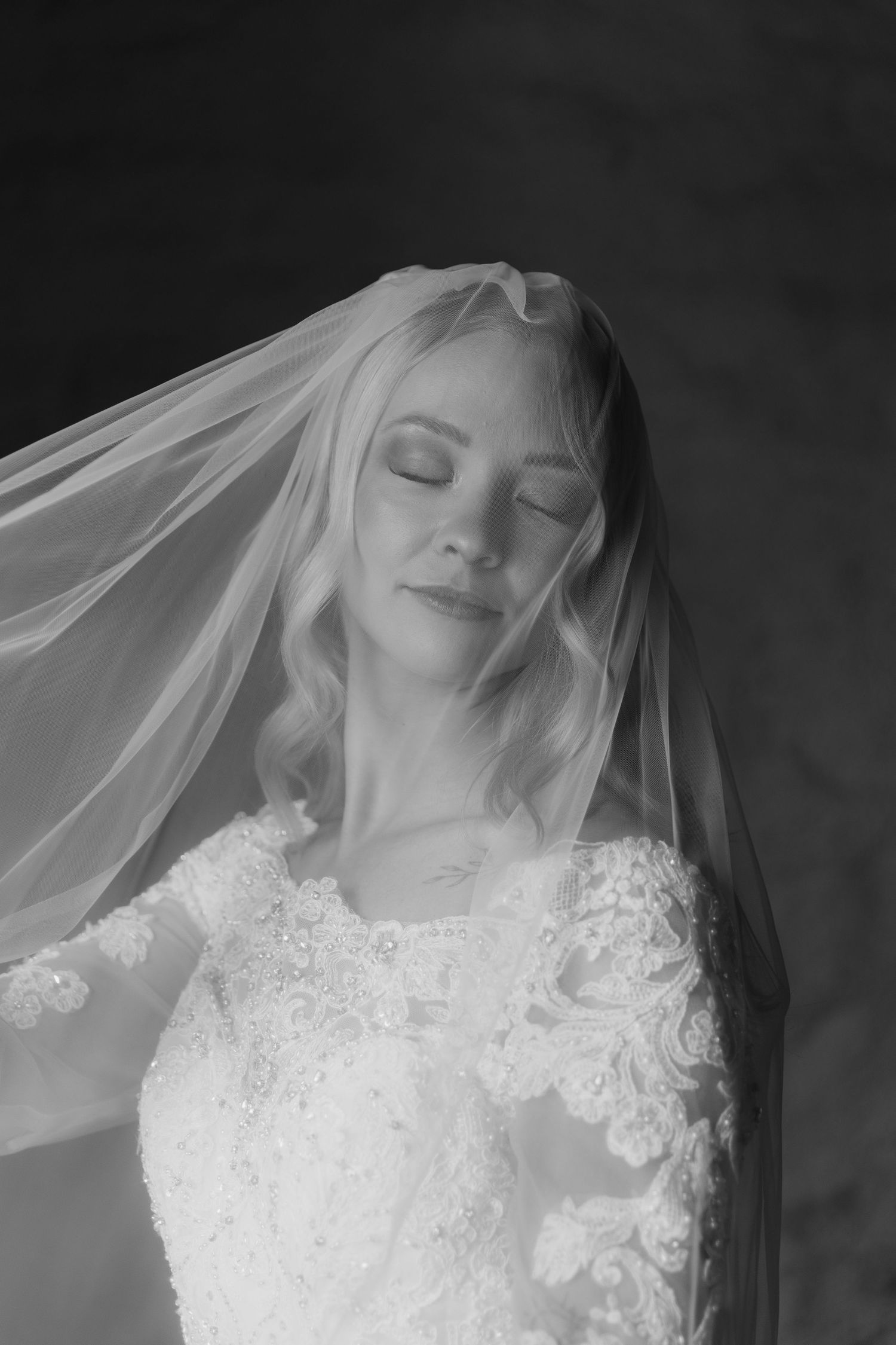 Black and white artistic bridal portrait showing delicate lace veil details.