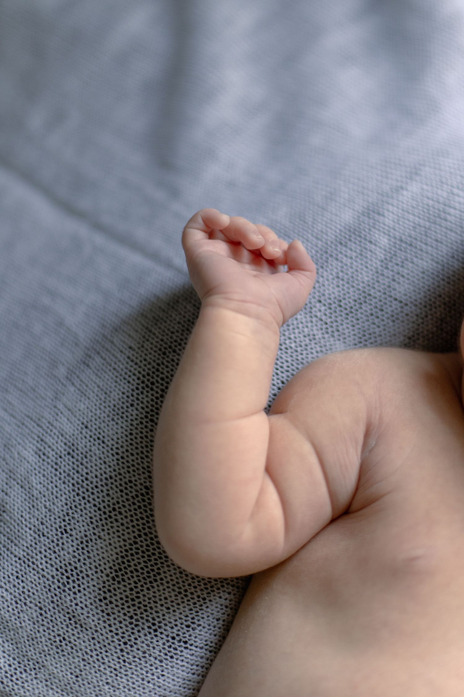 A series of close-up shots showing tiny baby feet and legs resting on gray fabric in different positions.