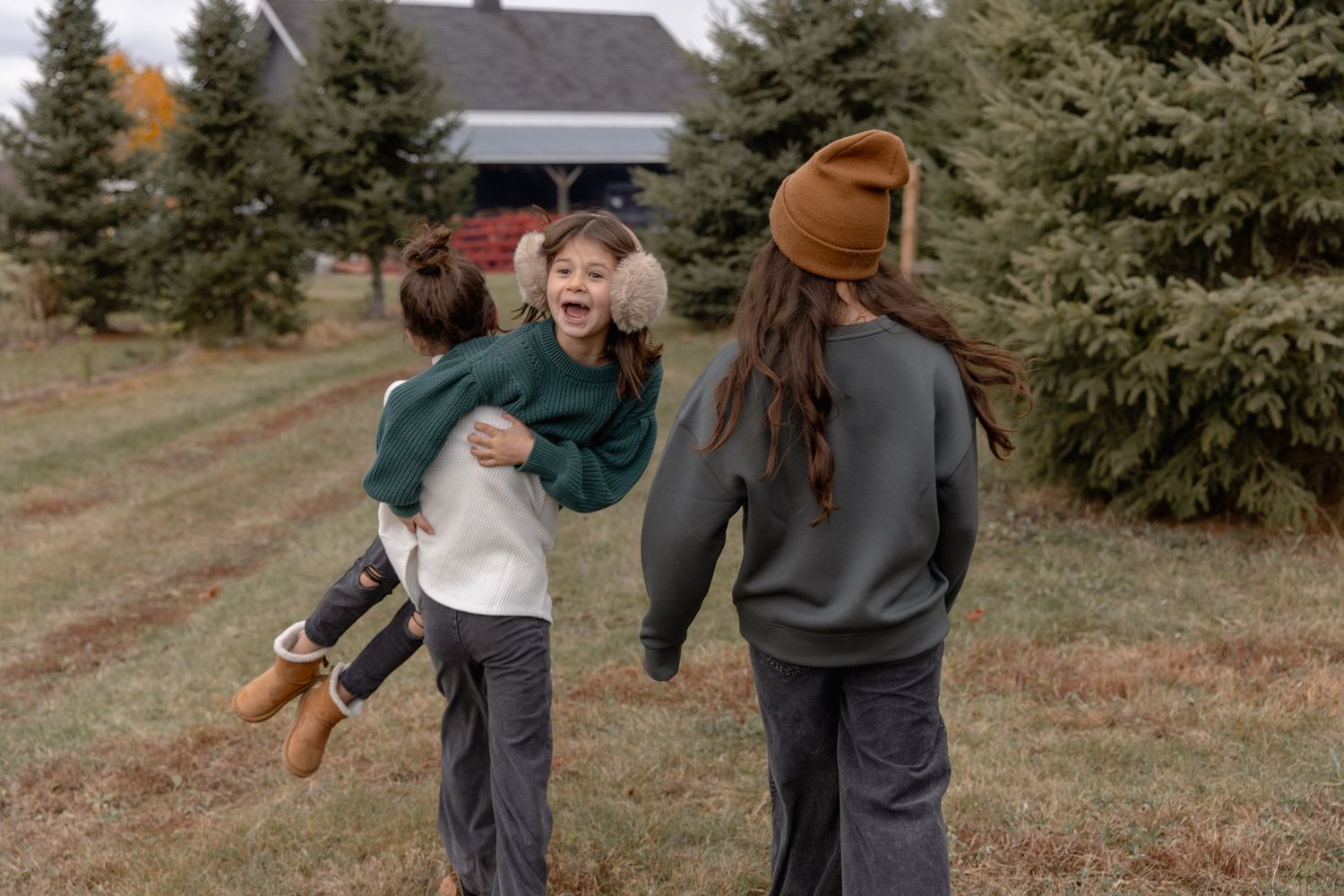 People enjoying a casual autumn day at a Christmas tree farm with evergreen trees in the background.