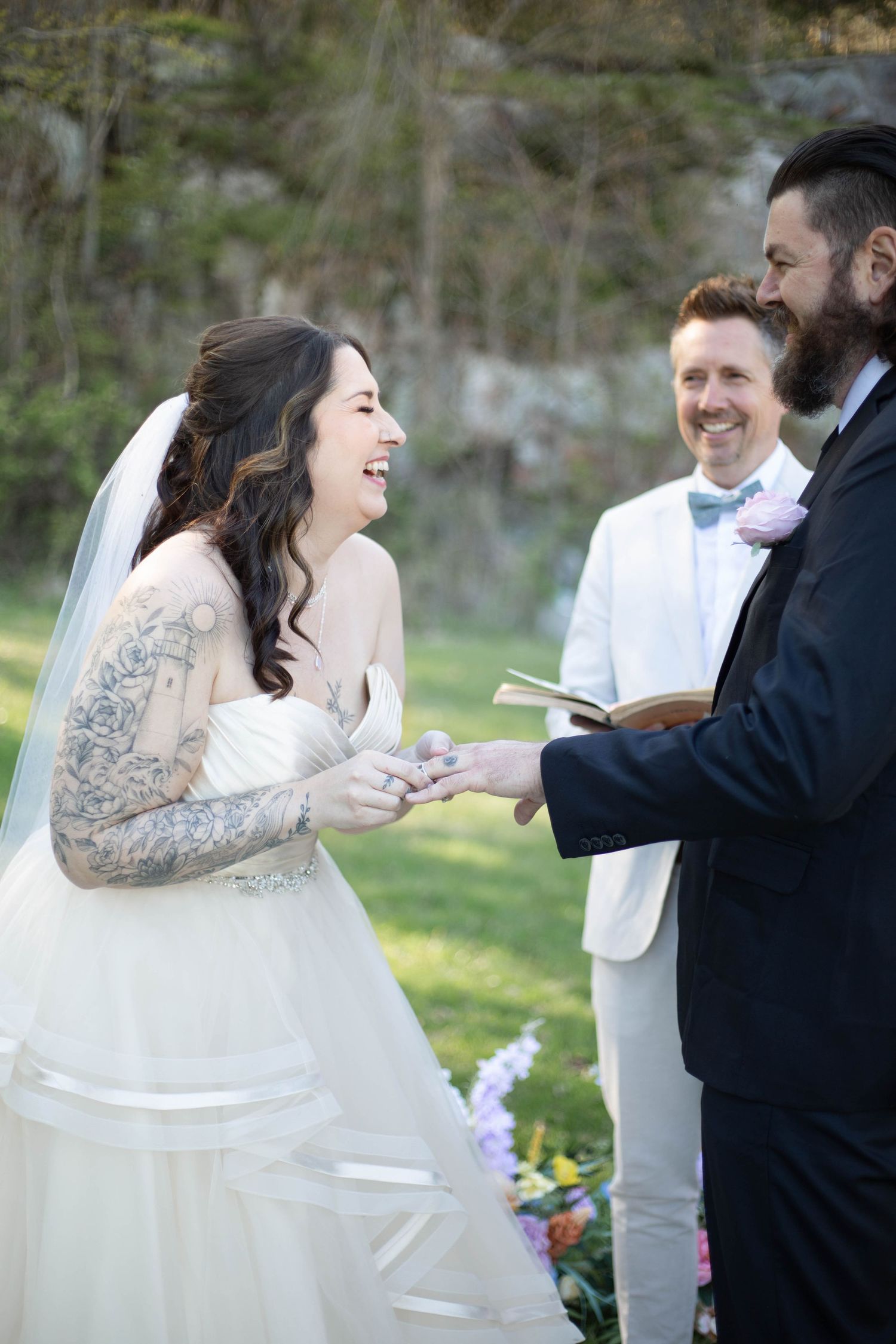 A couple shares a joyful moment during their outdoor wedding ceremony in a natural garden setting.