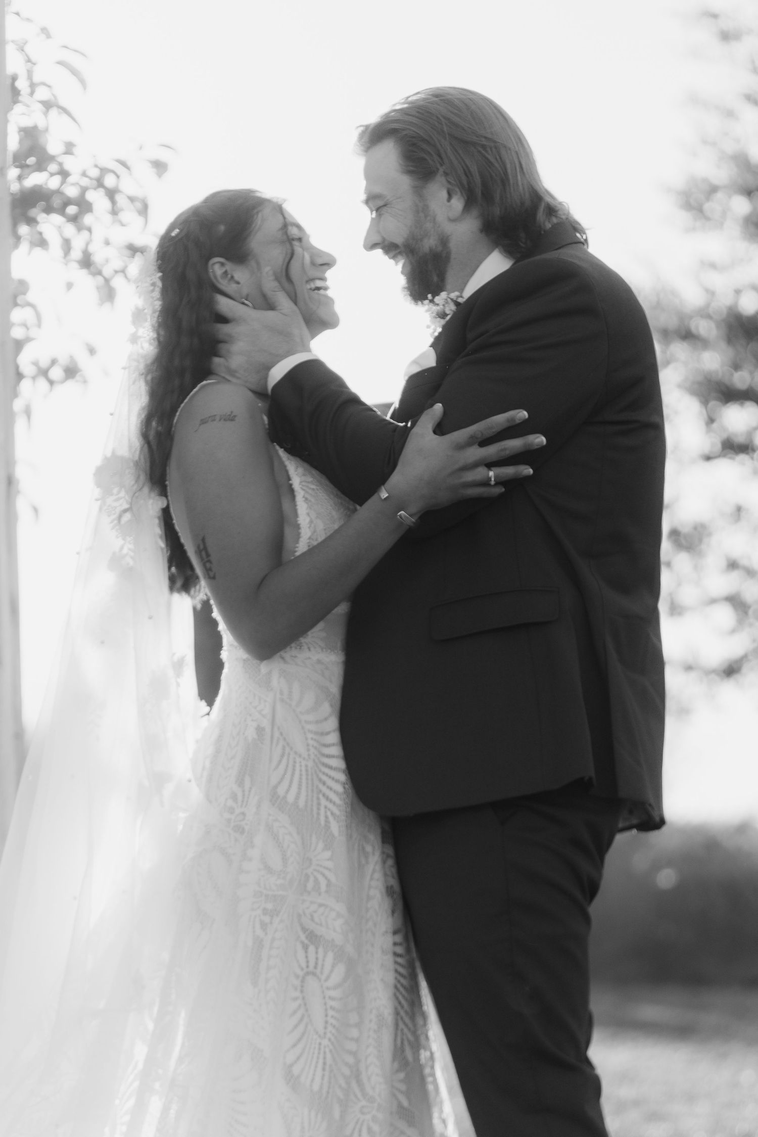 Black and white wedding photos show emotional first look moment between bride and groom in outdoor setting.