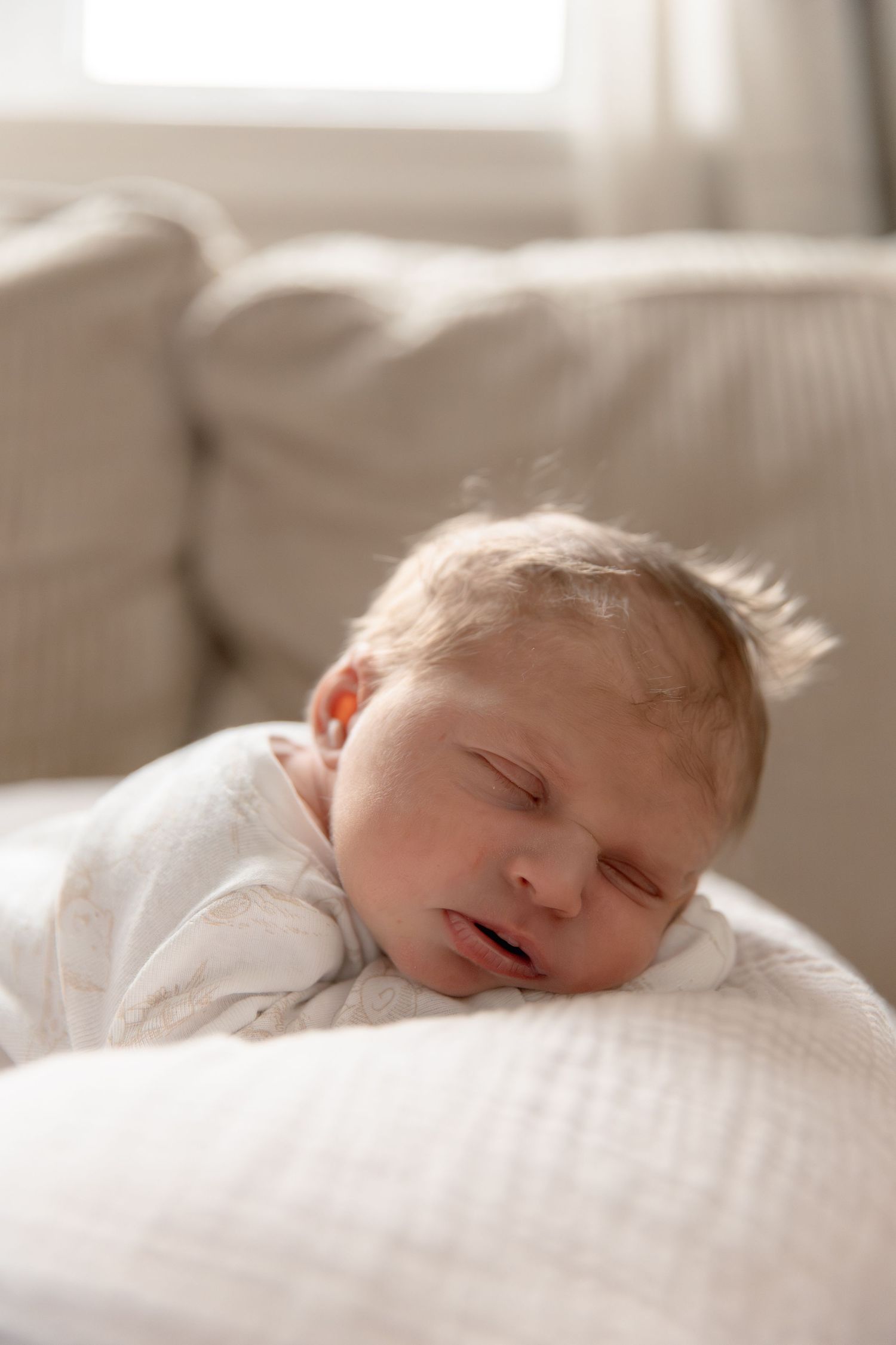 A sleeping baby rests peacefully on white bedding in a series of soft, serene photos.