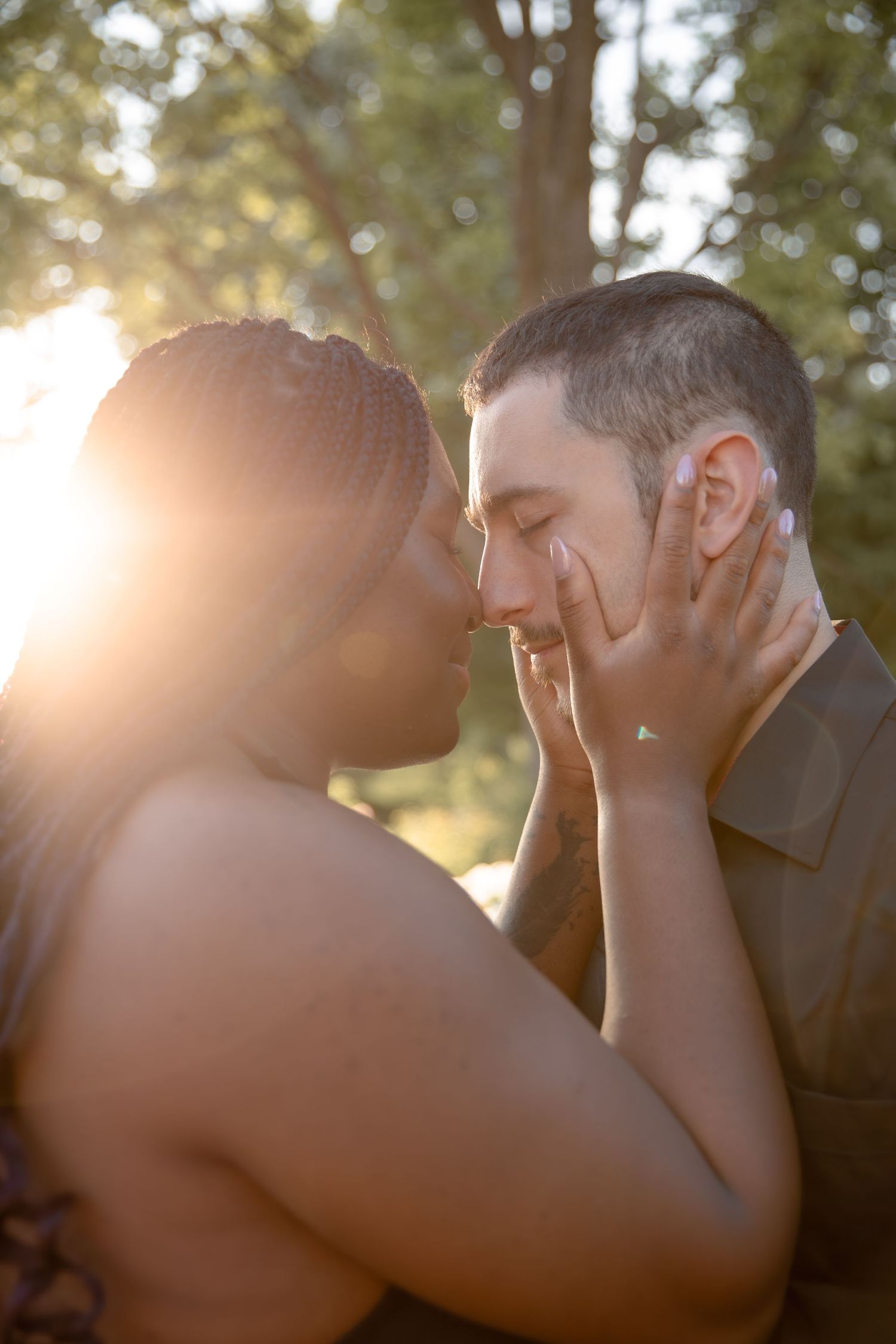 A tender moment between two people embracing in sunlit nature with soft bokeh effect in background.