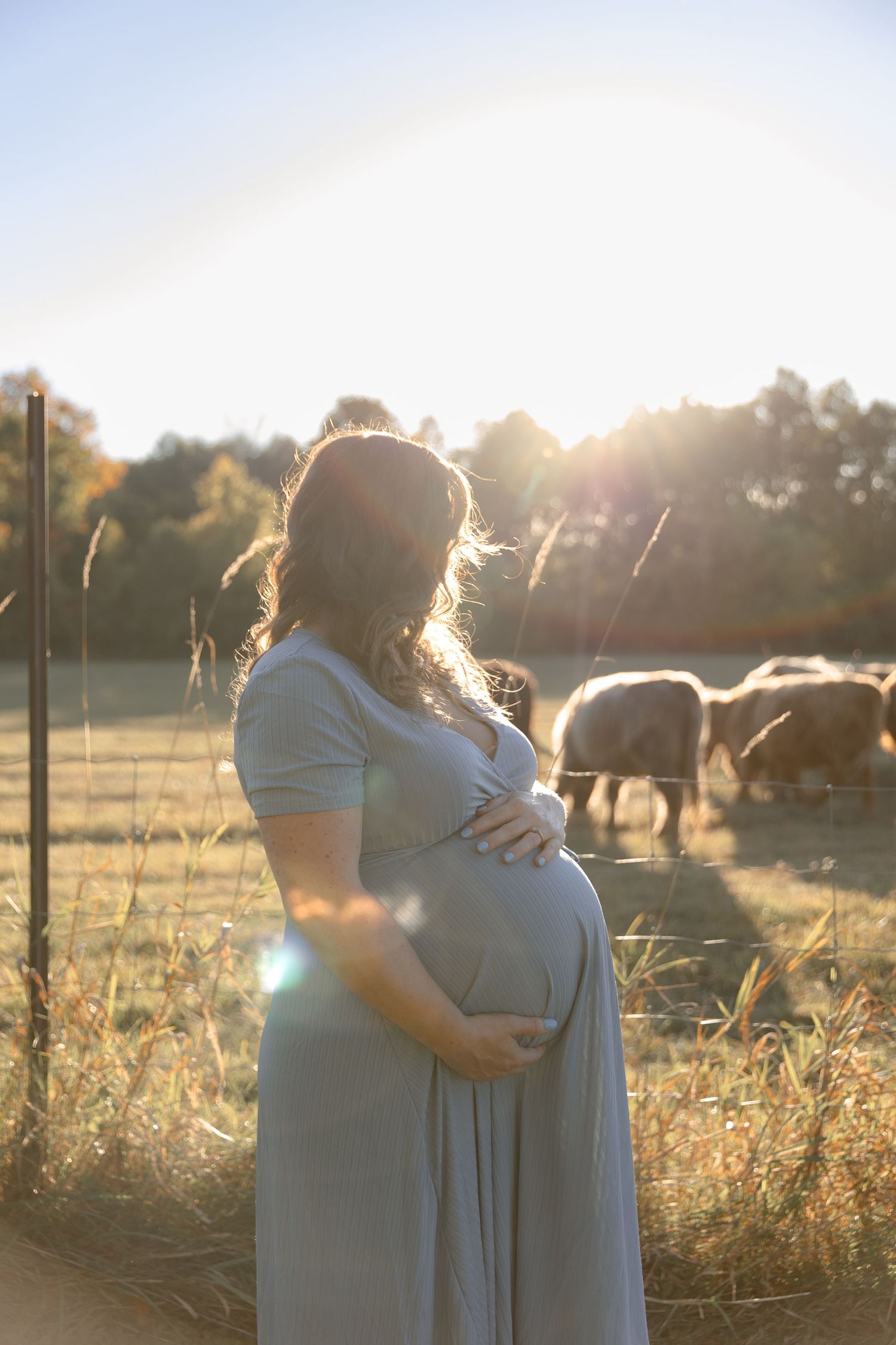A tender moment captured between two people in matching dresses during sunset in a rural field setting.