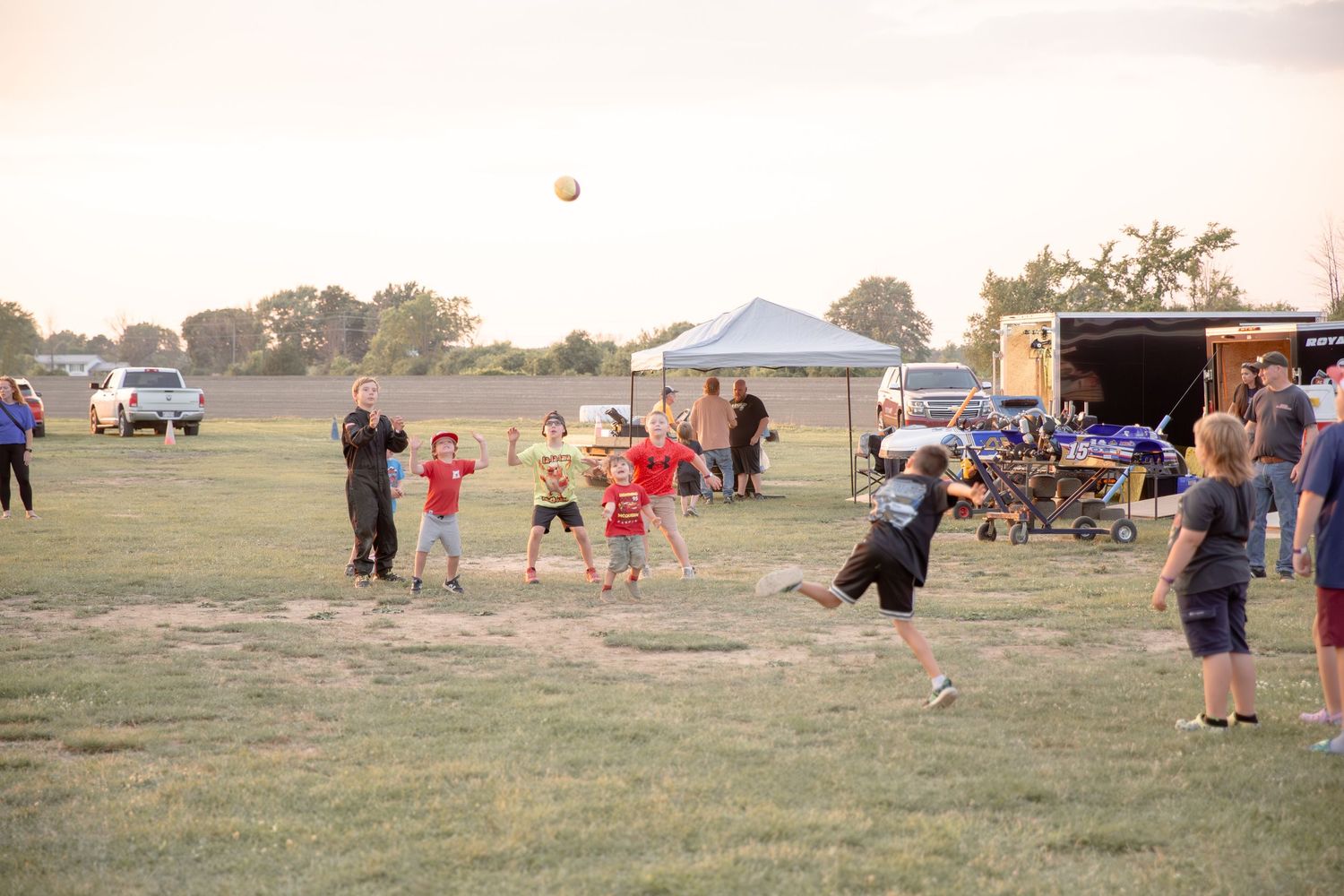Athletes gather outdoors on a grass field during a competitive event with tents and spectators visible in the background.