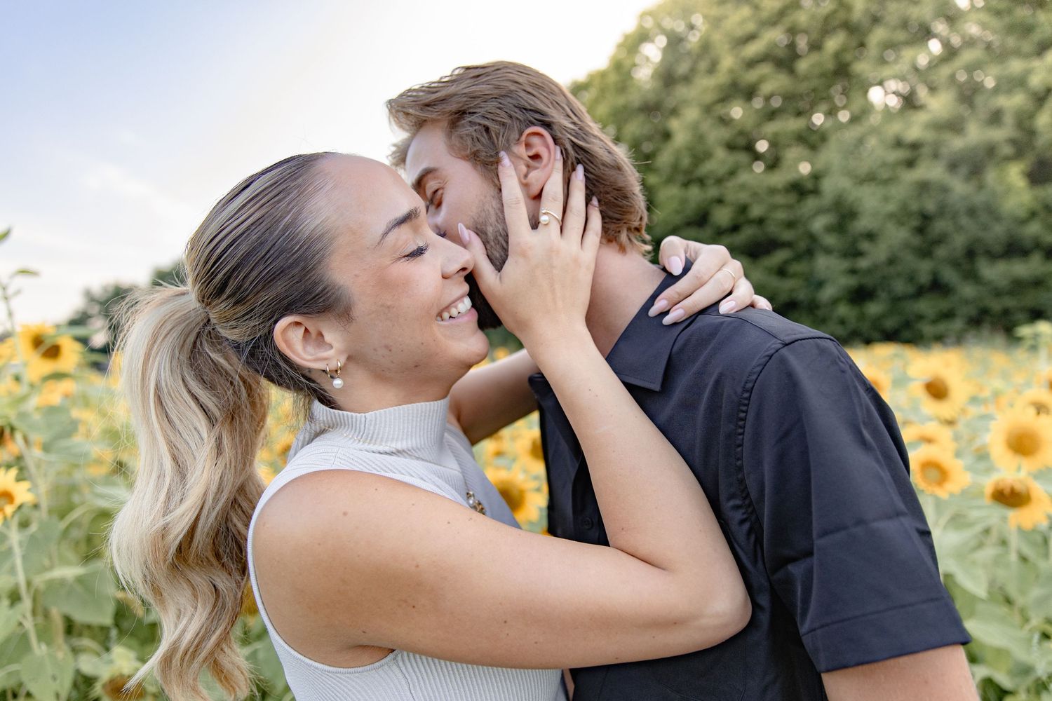 Romantic couple embracing in a blooming sunflower field during golden hour.