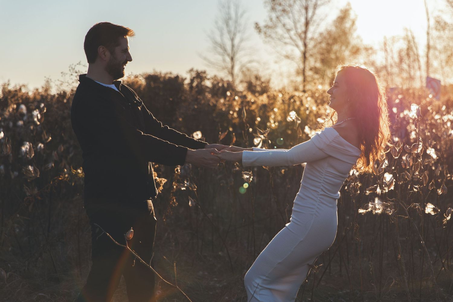 A couple dances together in a golden sunlit field at sunset, creating a romantic silhouette against the warm sky.