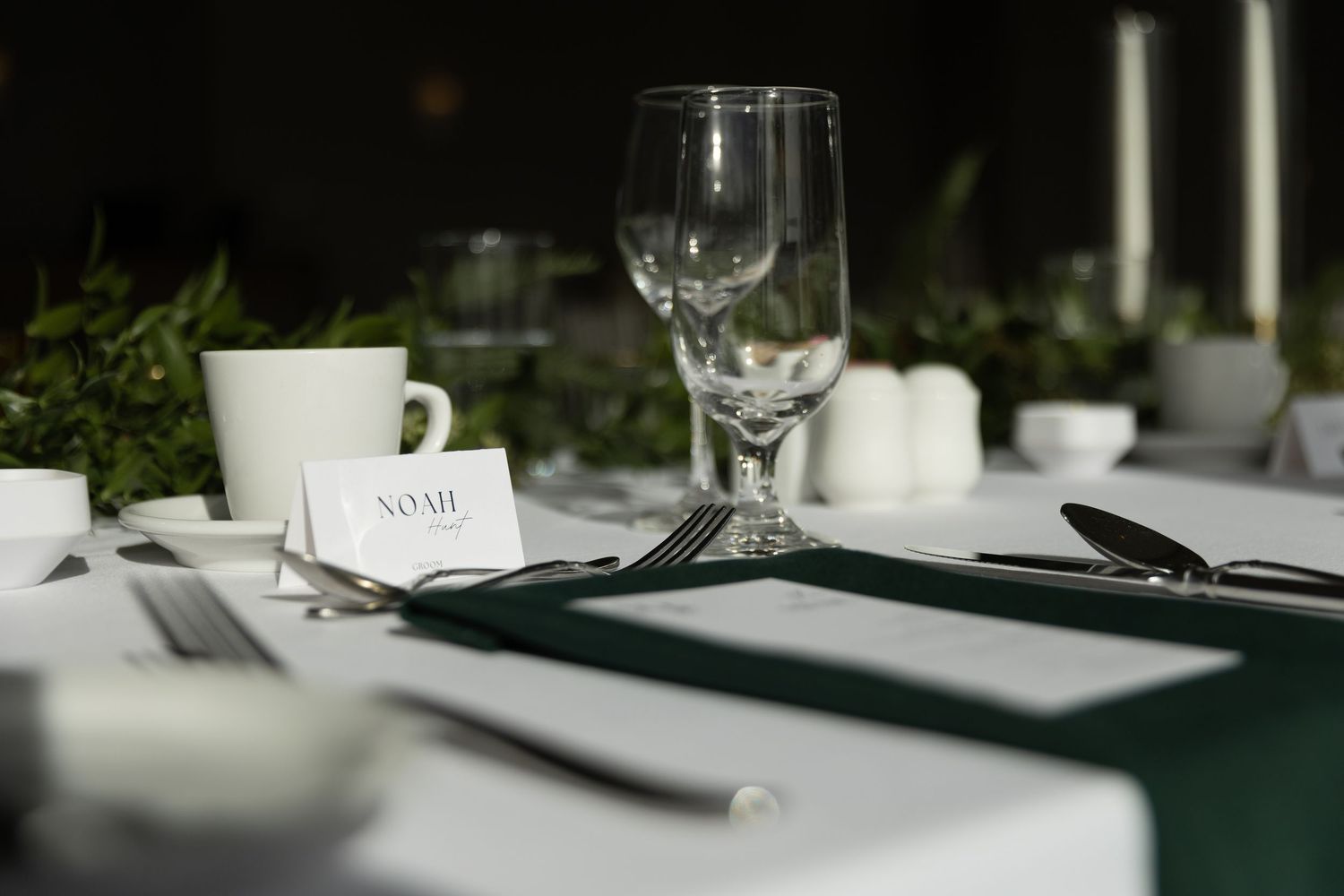 Elegant table settings with white linens, wine glasses, and place cards in a formal dining arrangement.