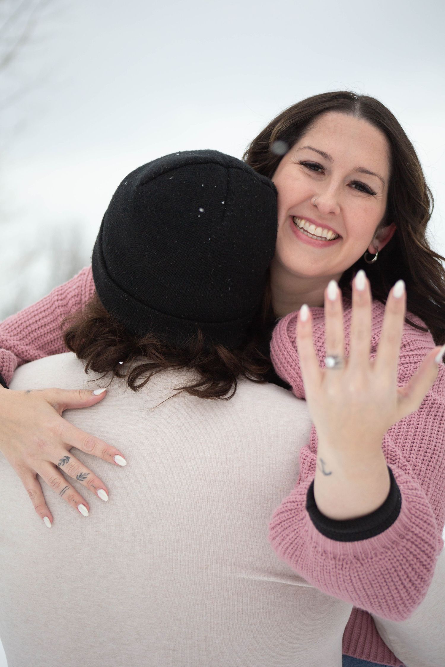 Close-up engagement photo showing off new ring with excited expressions in winter setting.