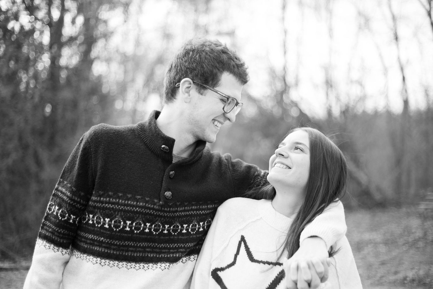 A black and white photo of two people laughing and embracing outdoors on a winter day.