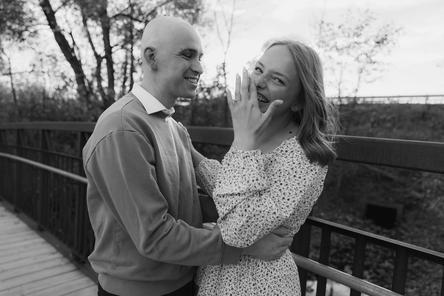 A romantic couple shares tender moments together on a bridge during a black and white photo session.