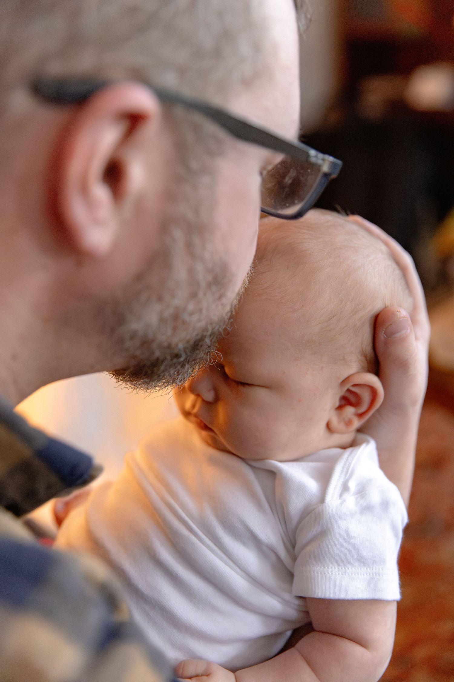 Close-up sequence showing parent giving gentle kisses to a baby in white clothing with warm lighting.