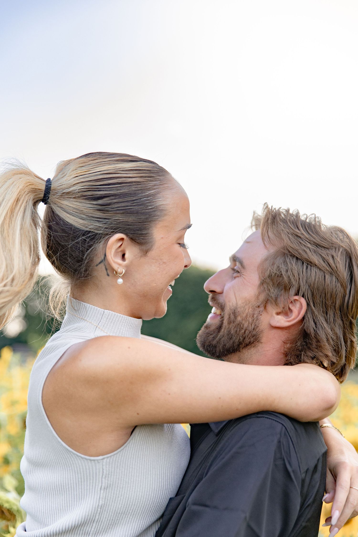 A couple shares a tender moment in a series of romantic outdoor photos against a blurred natural background.