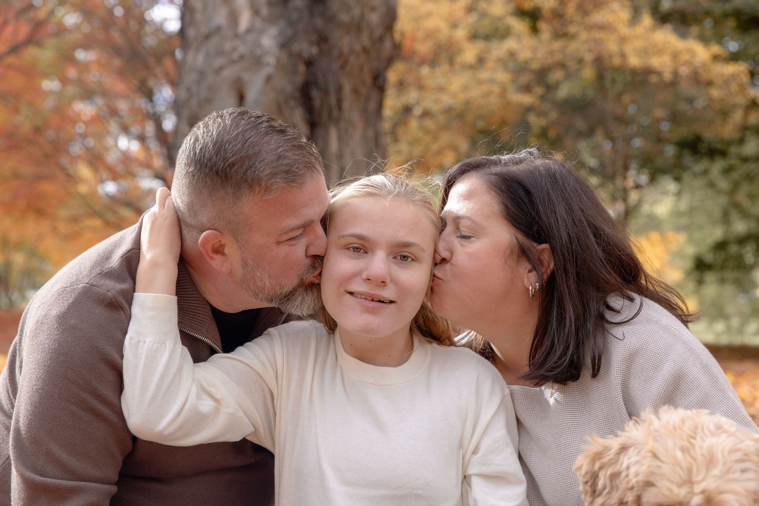 Family embracing and sharing affectionate moments together during autumn outdoor photo session.