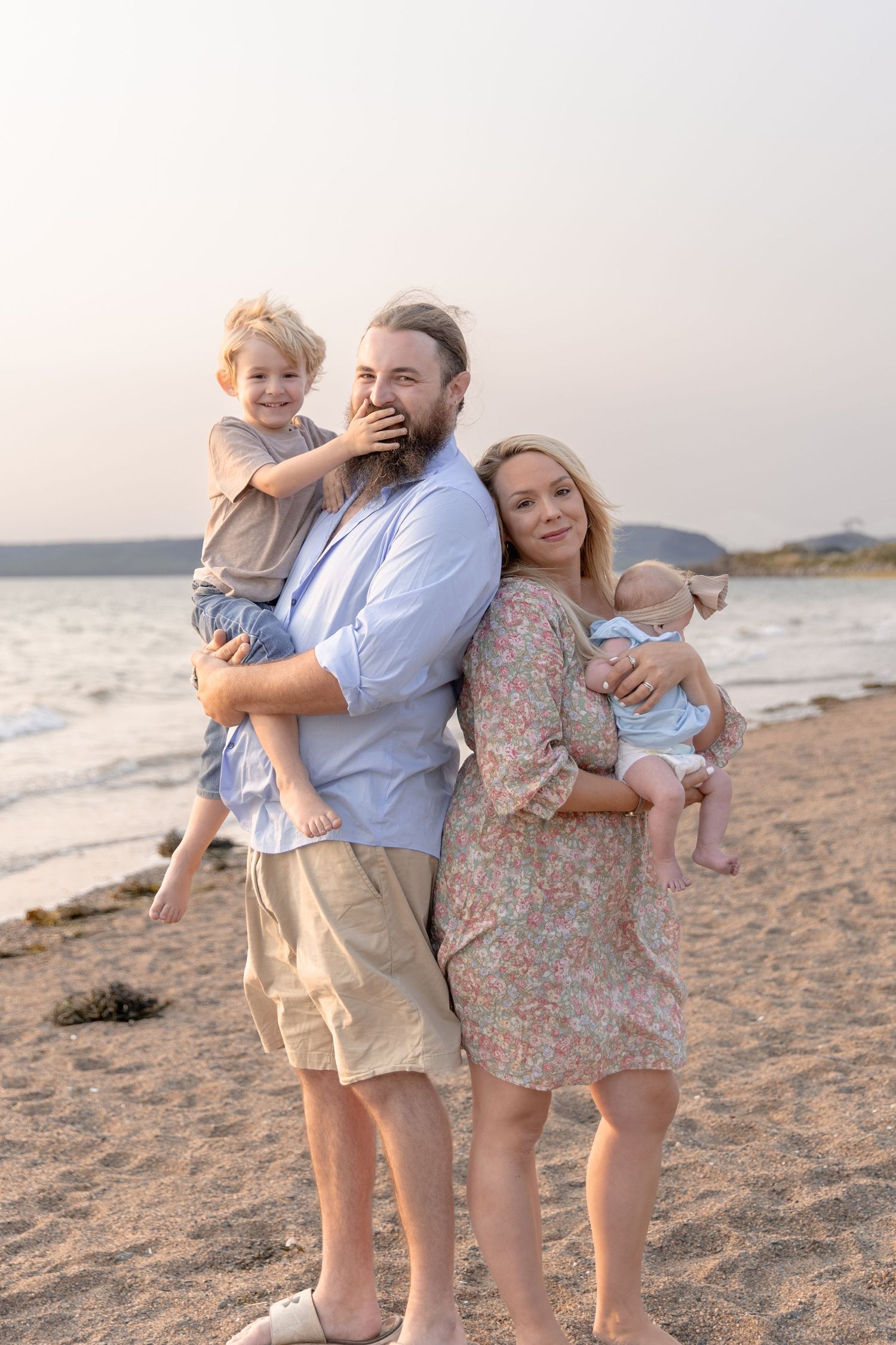 Happy family spending time together on a sunset beach with young children enjoying a tender moment.