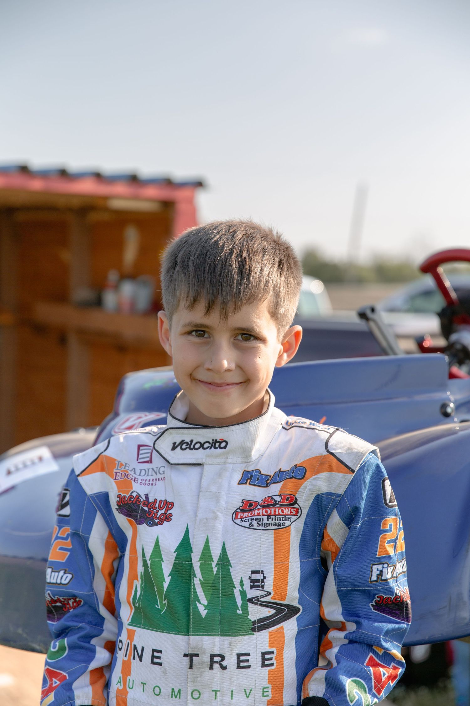 A racing suit with Pine Tree Automotive branding shown from different angles and details.