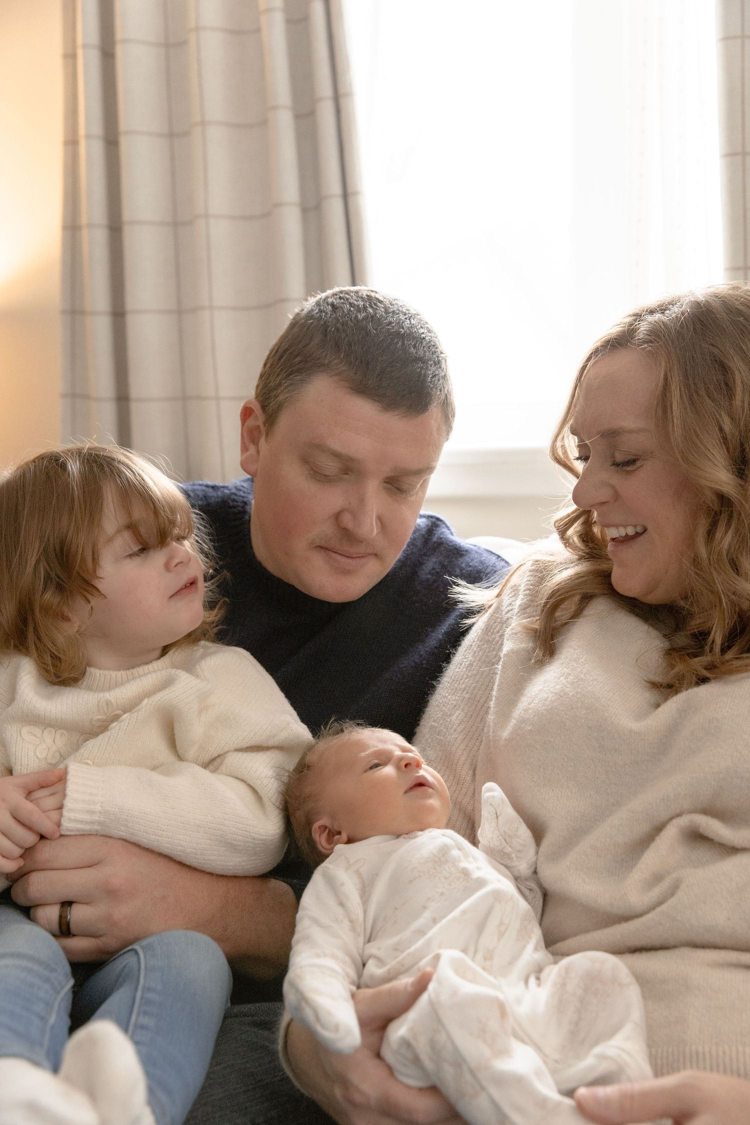 A heartwarming collage shows a family cuddling together on a couch in cozy cream sweaters.