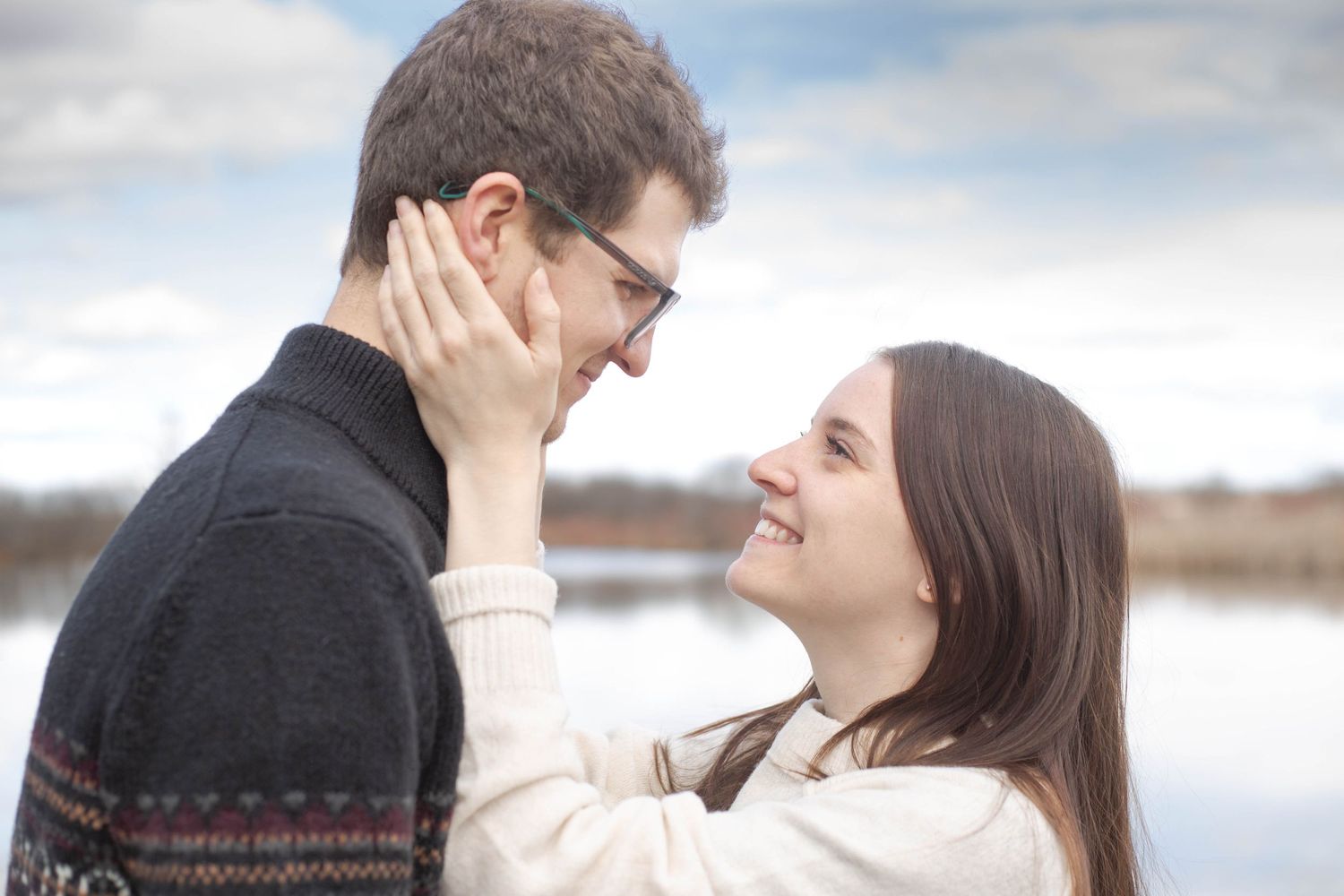 Two people share an intimate romantic moment outdoors with a winter landscape in the background.