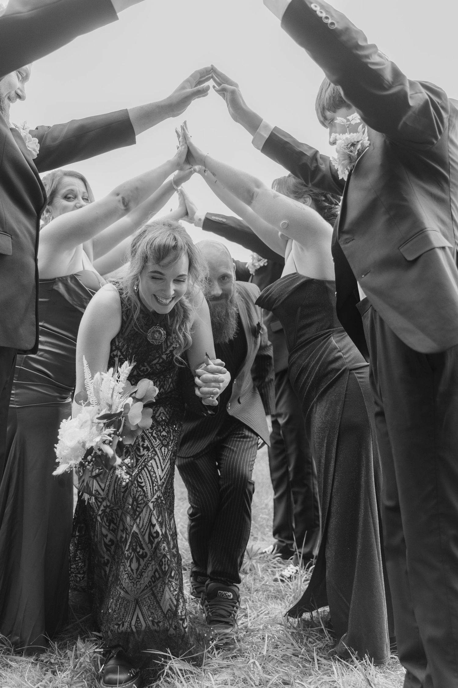 A group of people in dark formal attire dance and celebrate together at a festive gathering.