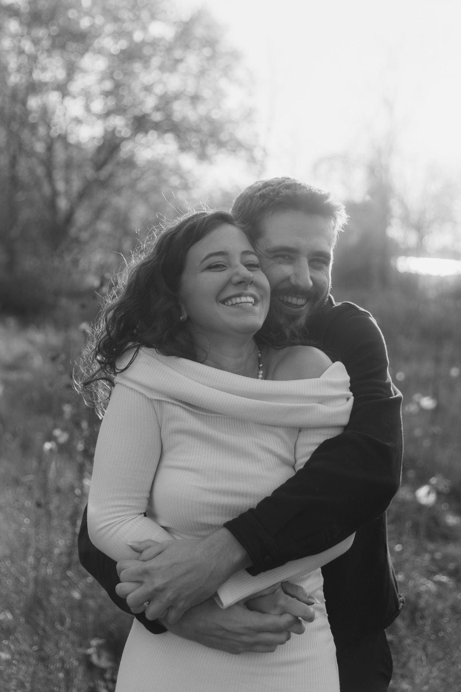 A couple embraces lovingly in a black and white outdoor photoshoot series with natural lighting.