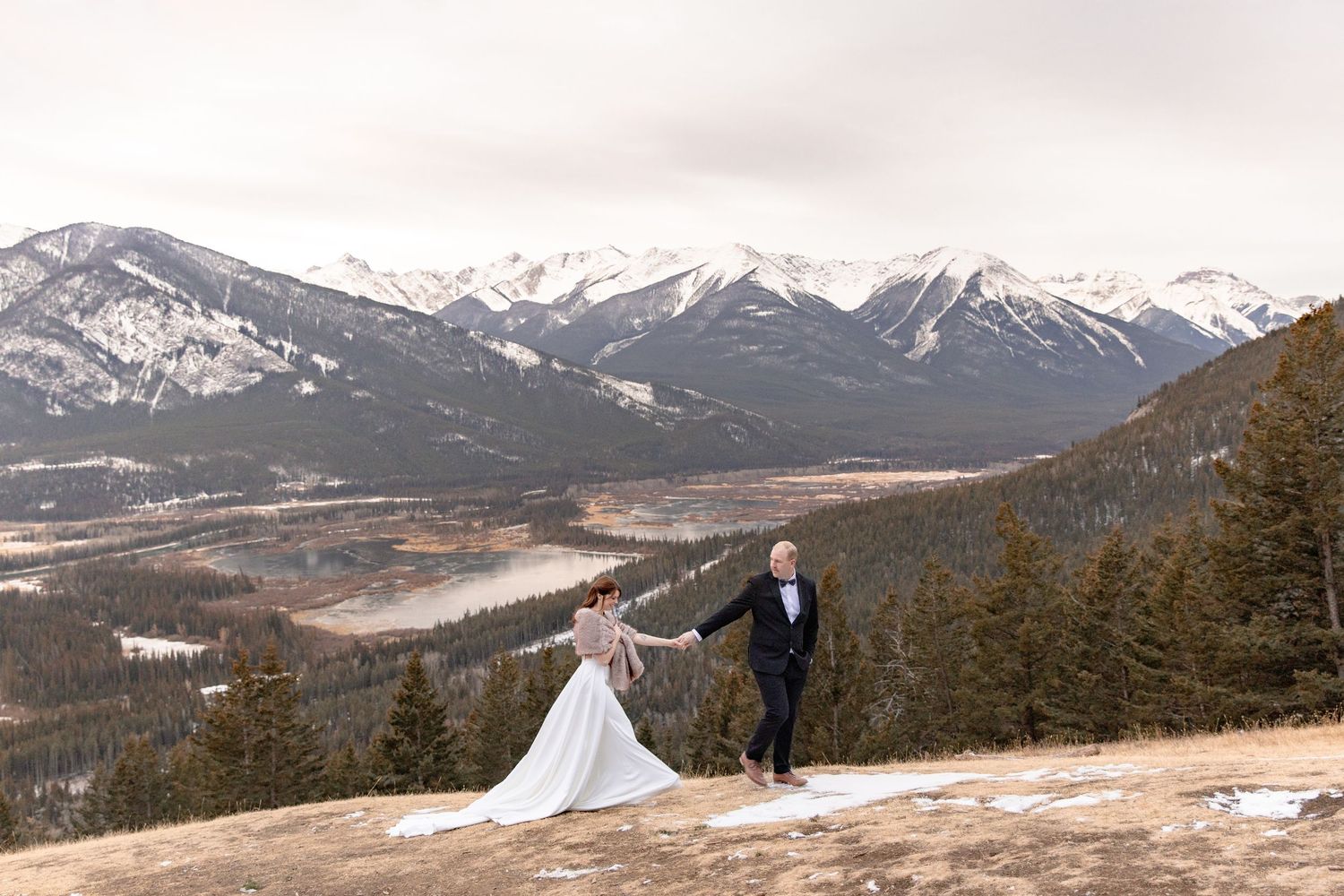 A panoramic winter mountain landscape with snow-capped peaks and evergreen forests stretching across multiple connected views.