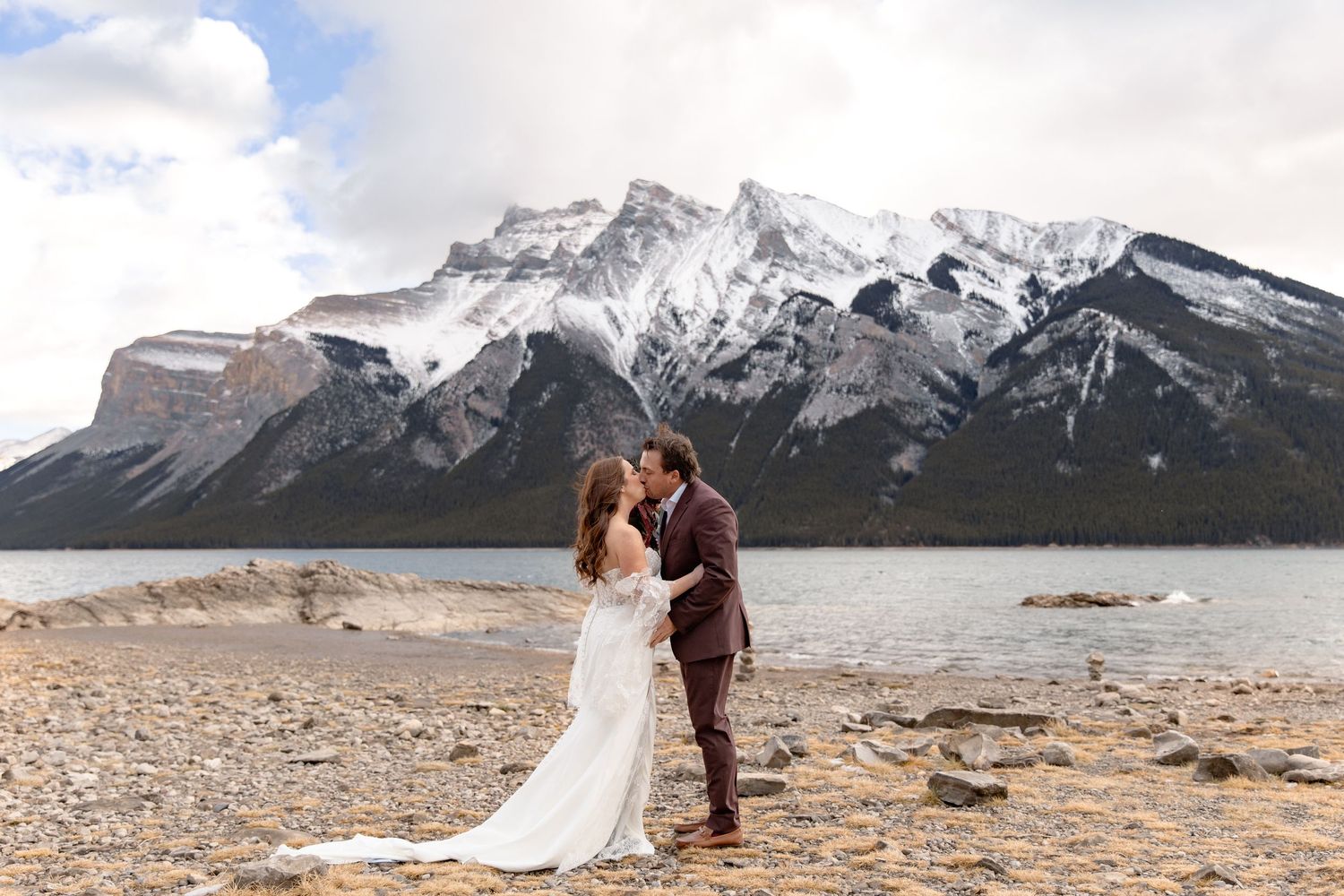 A romantic mountain elopement photo series showing a couple against snowy peaks at Lake Minnewanka in Banff National Park.