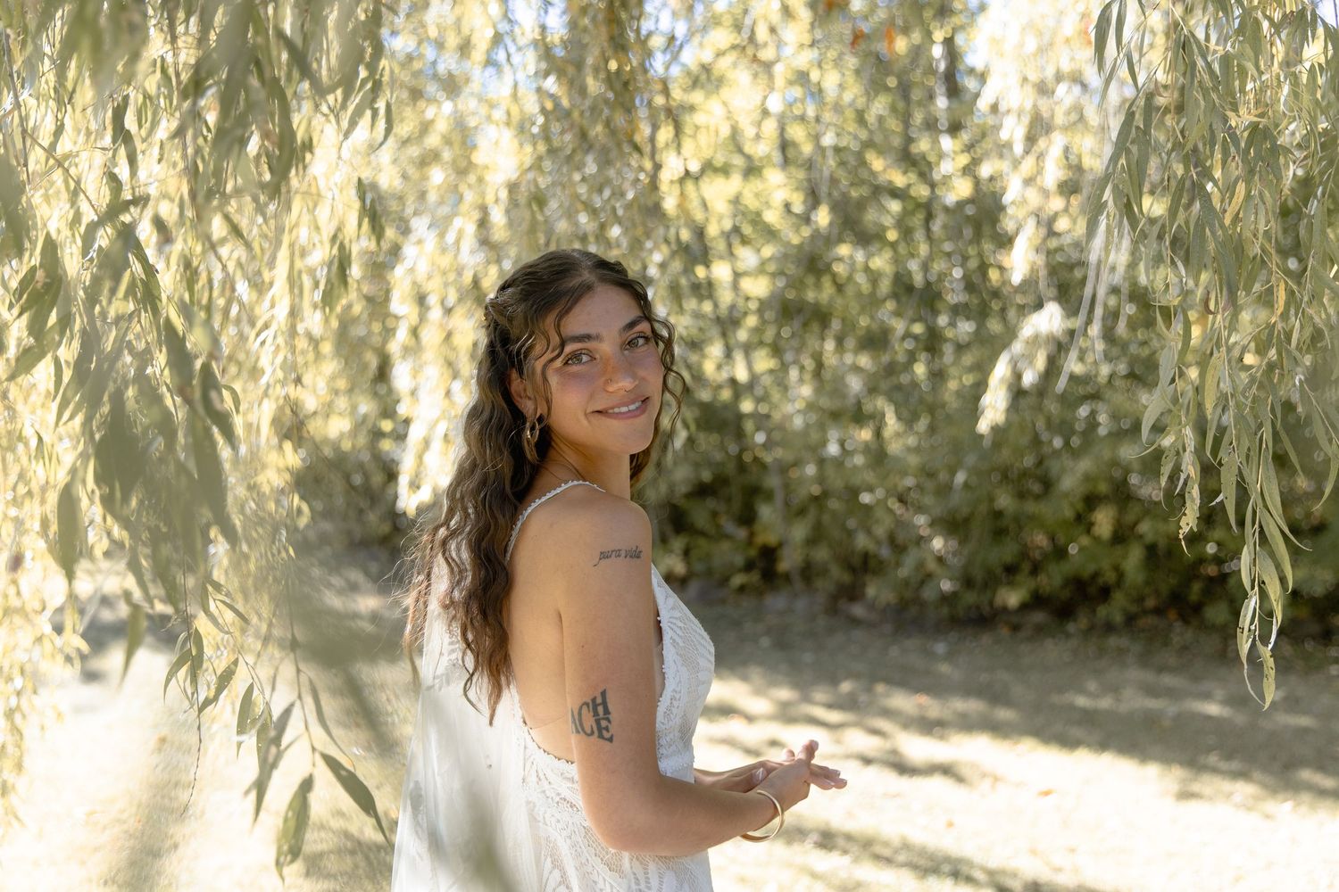 Sunlit portrait under weeping willow branches with golden afternoon light.
