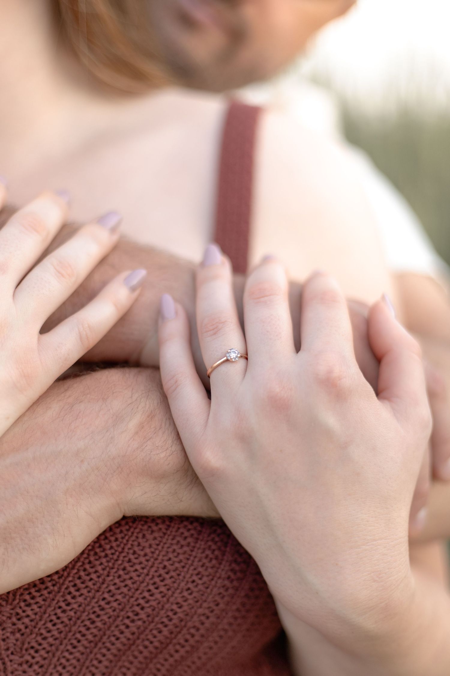 A close-up sequence showing hands wearing a delicate engagement ring against a burgundy knit sweater background.