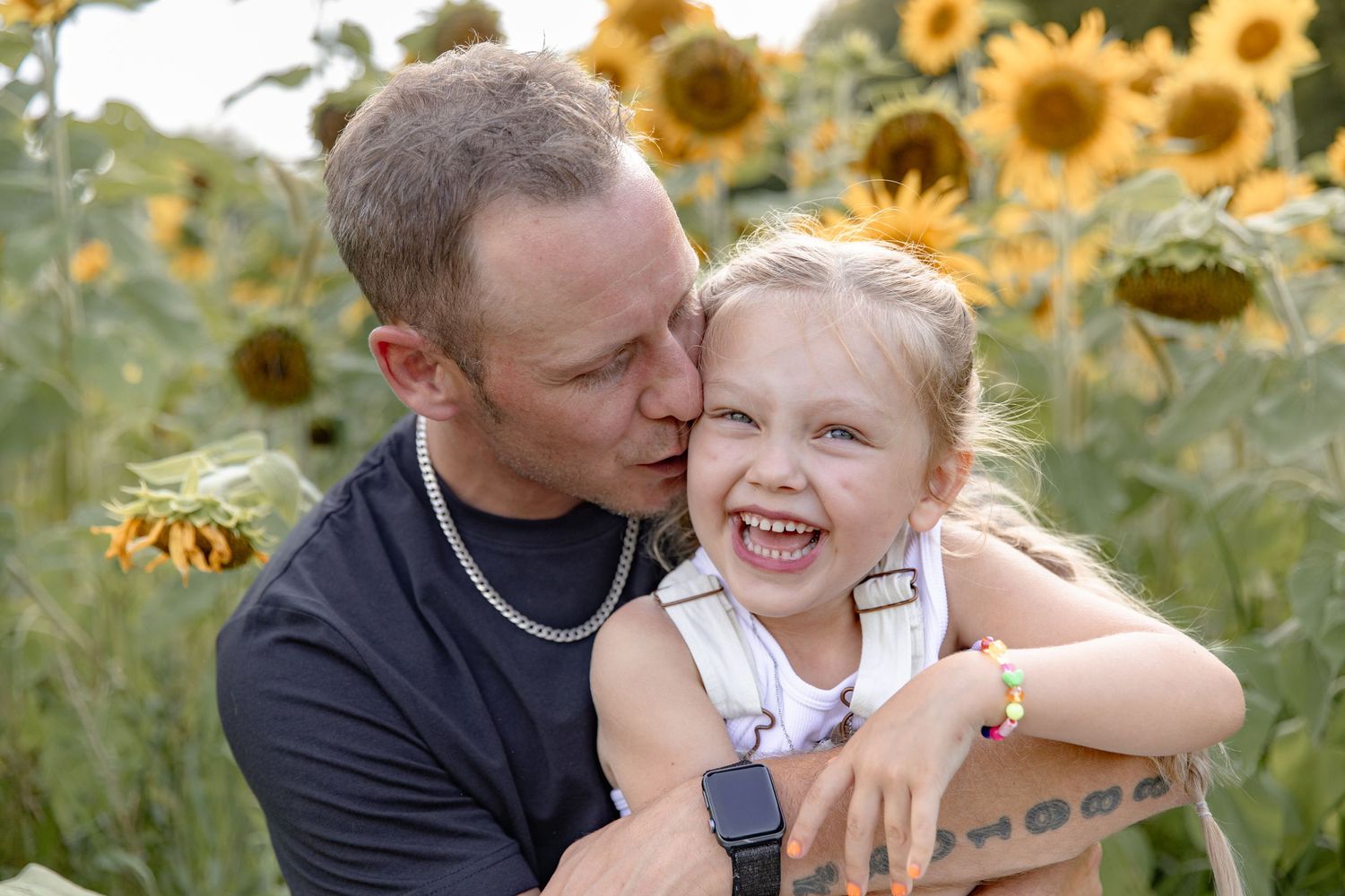 A loving family moment captured in a sunflower field during golden hour with bright yellow blooms surrounding them.