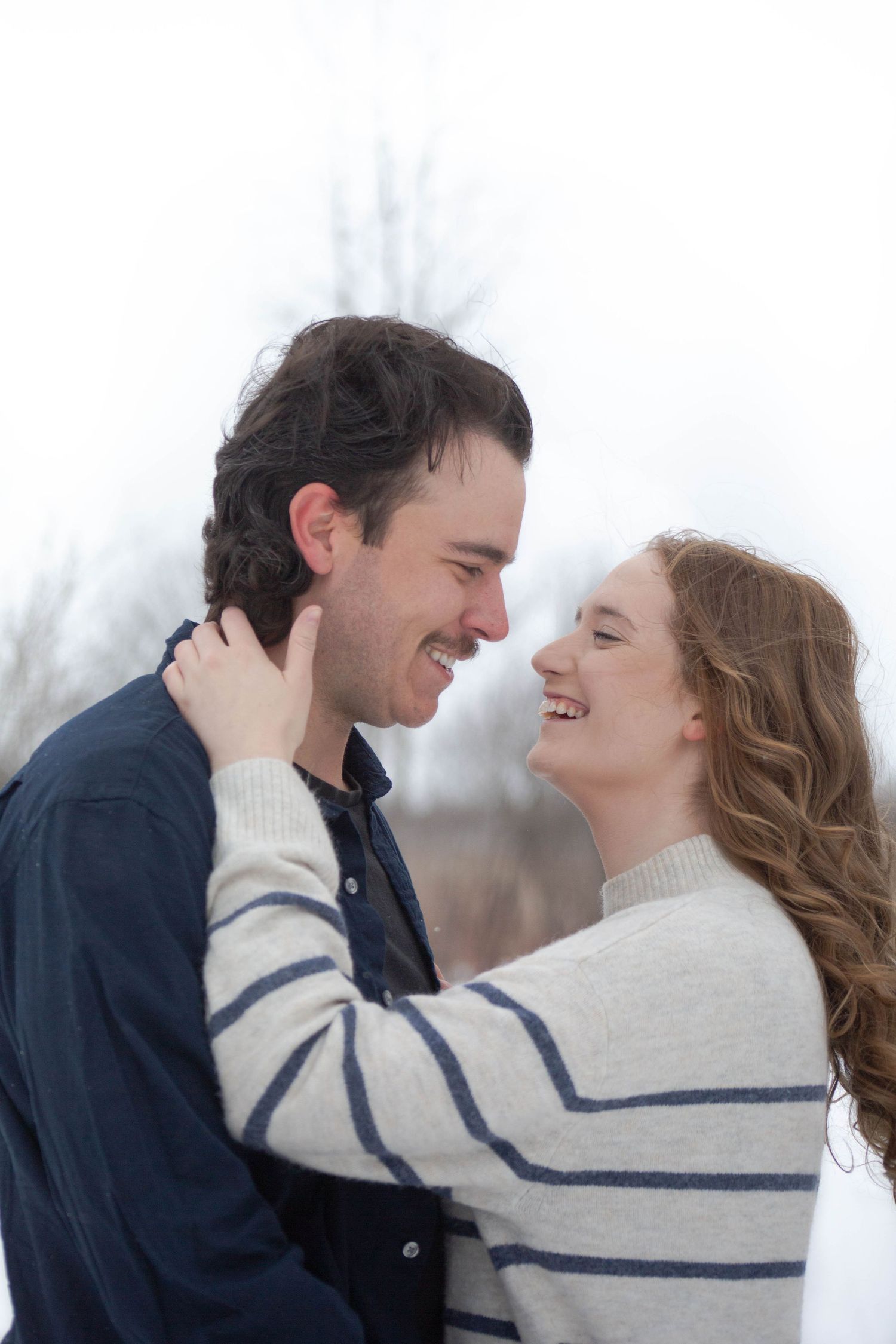 A candid moment of laughter between a couple during their winter engagement session.